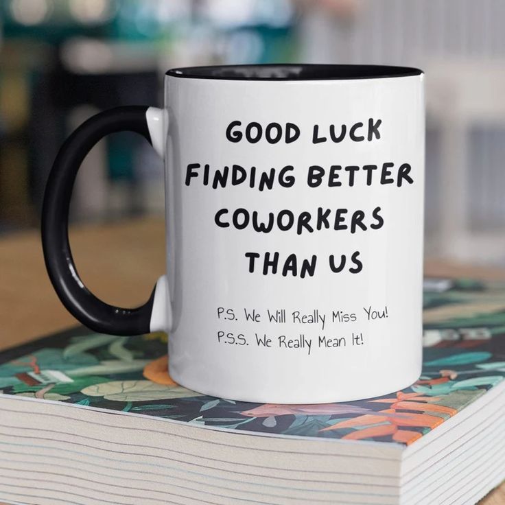 a black and white coffee mug sitting on top of a stack of books that says, good luck finding better coworkers than us