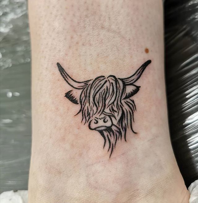 a black and white photo of a cow's head on the ankle tattoo design