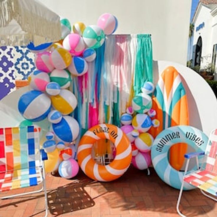 an assortment of colorful balloons and beach balls on display in front of a white building