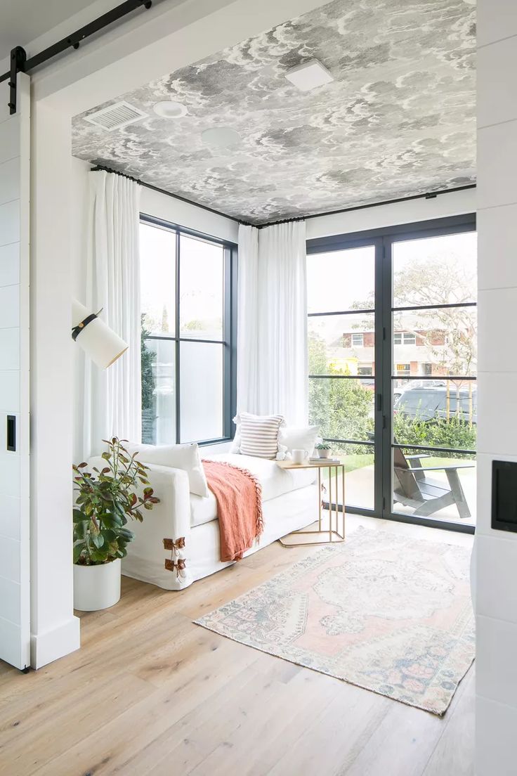 a living room filled with furniture and a window covered in white drapes next to a wooden floor