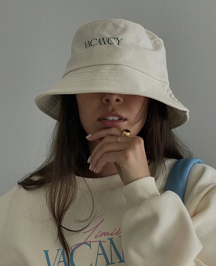 a woman wearing a white bucket hat with the words vacan written on her chest