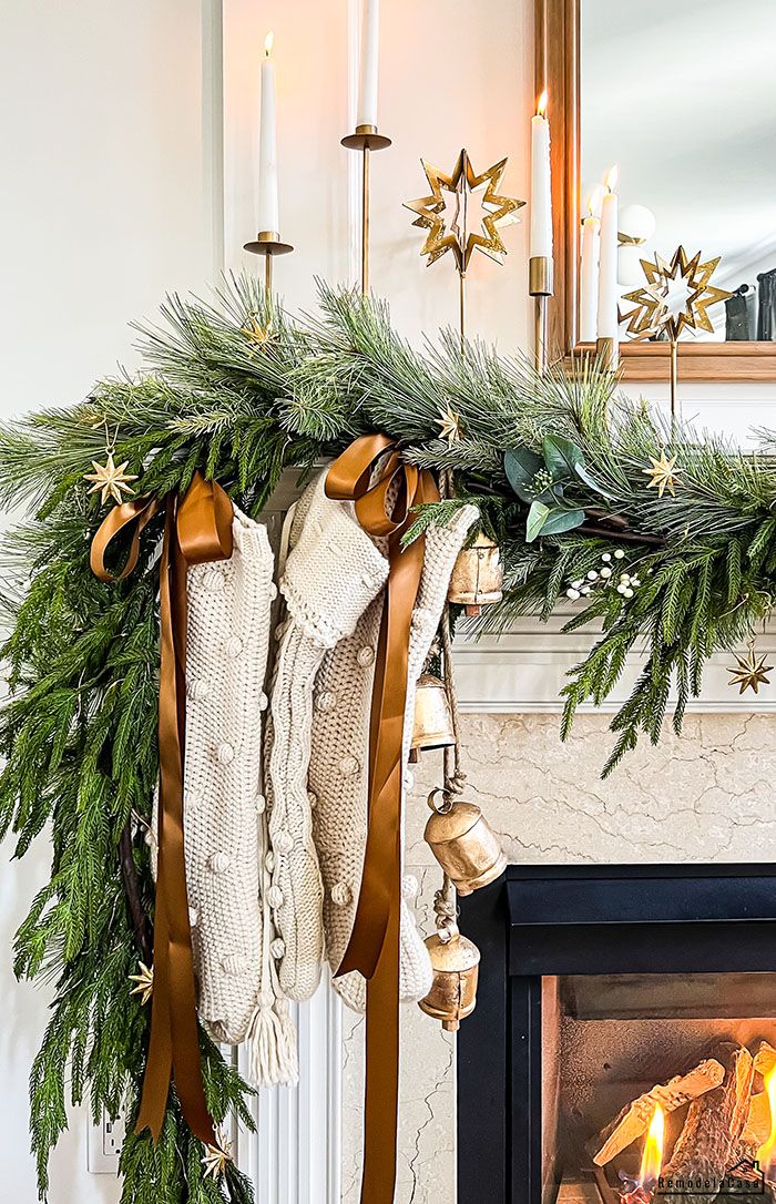 stockings hanging from a mantle with candles and christmas decorations on it, next to an open fire place