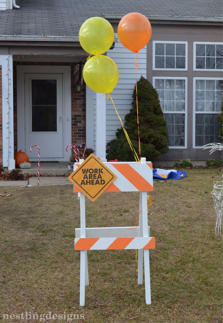 a construction sign with balloons on it in front of a house