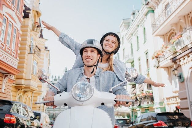 a man and woman riding on the back of a scooter