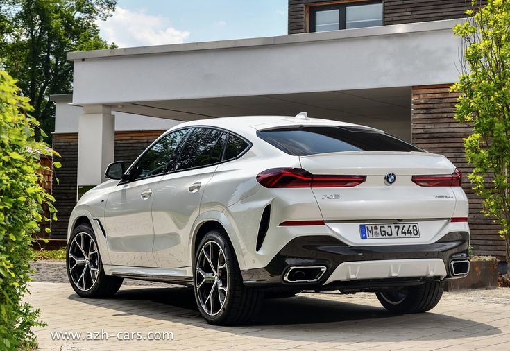 a white bmw suv parked in front of a house