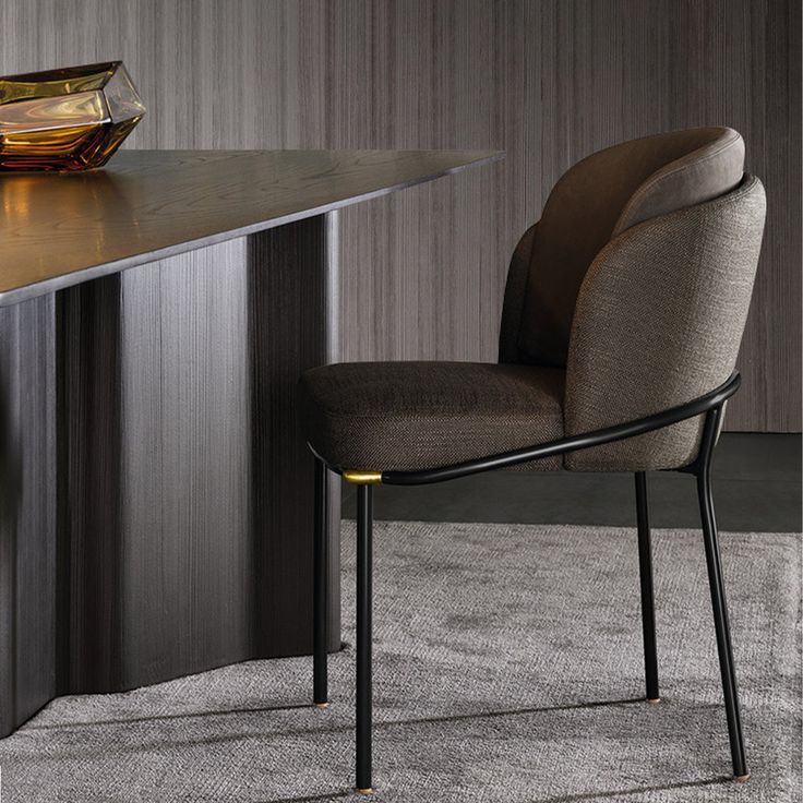 a chair sitting on top of a carpeted floor next to a wooden table and vase