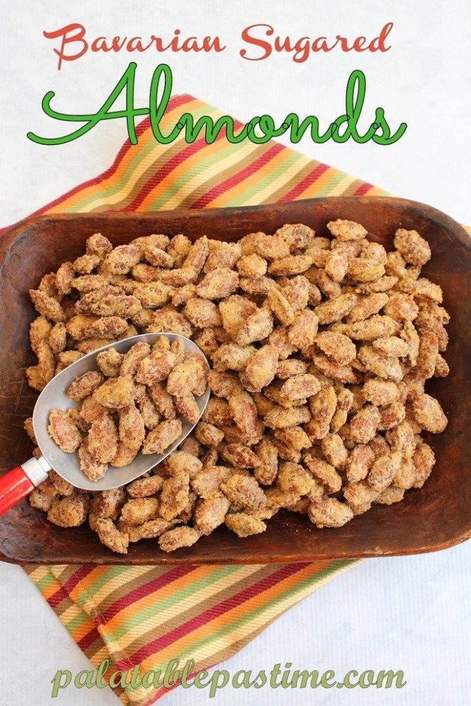 a wooden tray filled with nuts on top of a striped table cloth next to a spoon