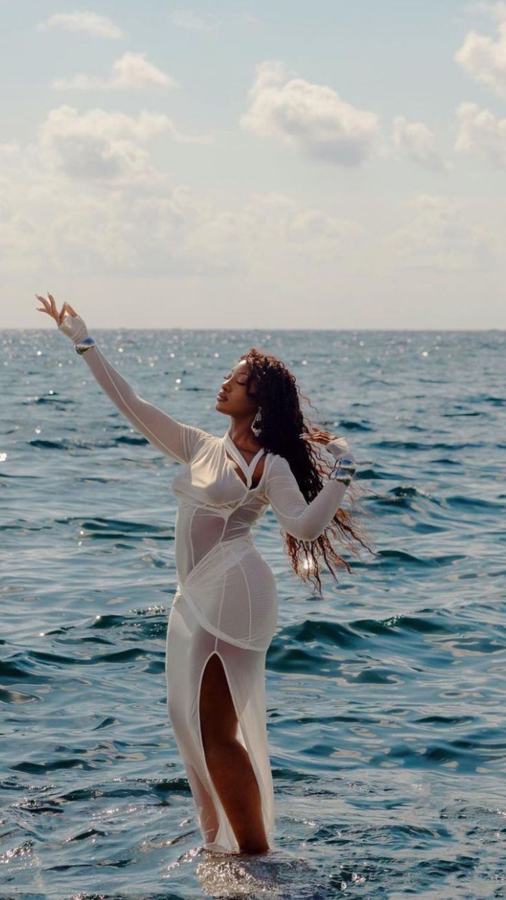 a woman standing in the water with her arms outstretched