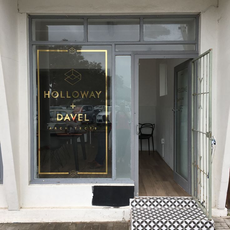 a store front with a black and white patterned bench in the foreground next to it