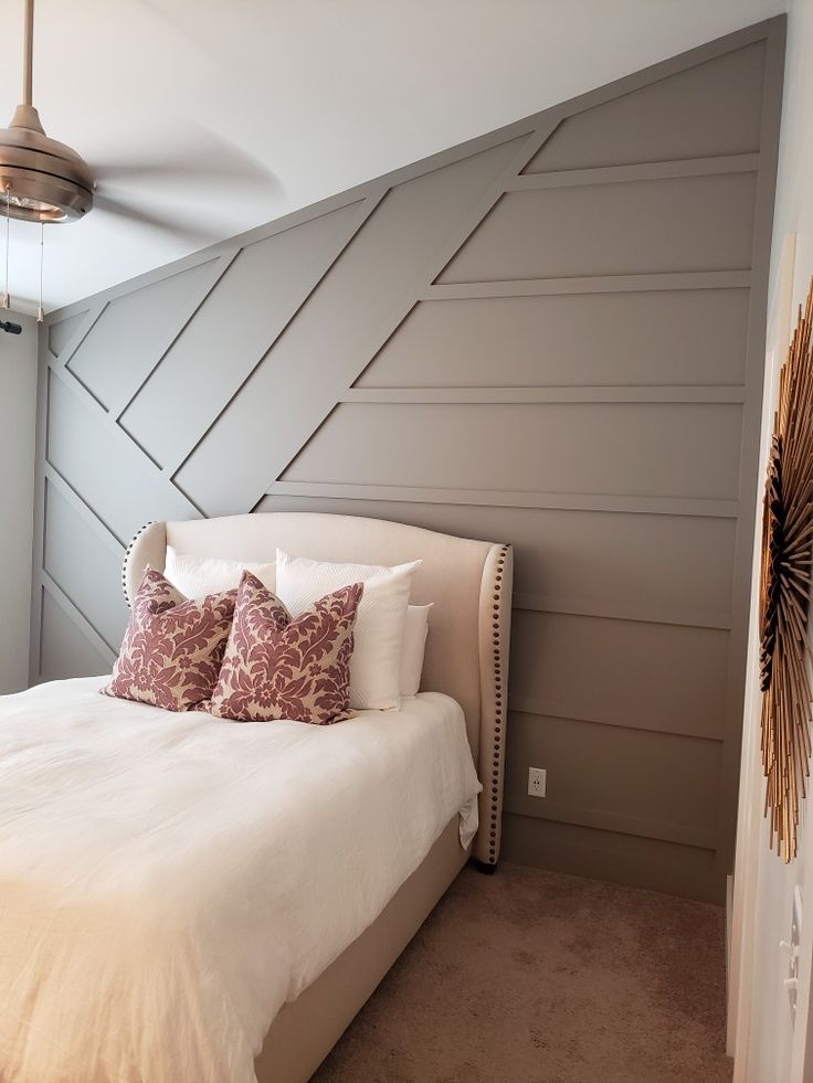 a white bed sitting in a bedroom next to a wall mounted fan and light fixture