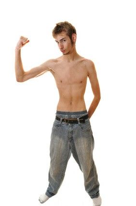 a shirtless man is posing with his hands in the air while wearing jeans and white socks