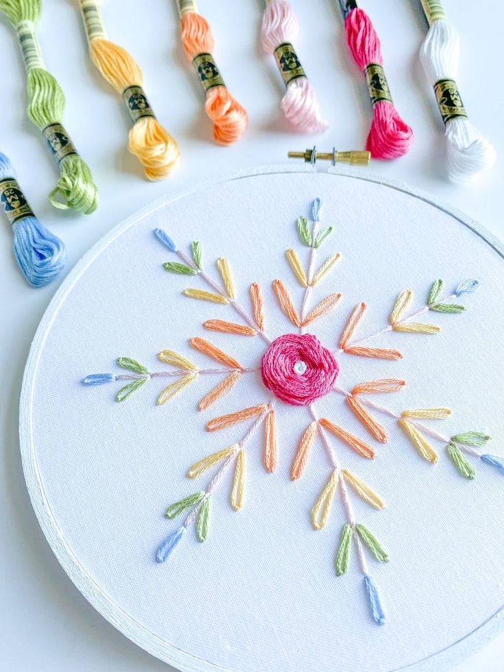 the embroidery is being worked on with different colored threads and needles, along with some crochet hooks