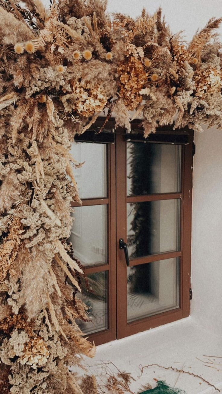 the window is decorated with dried plants and foliage