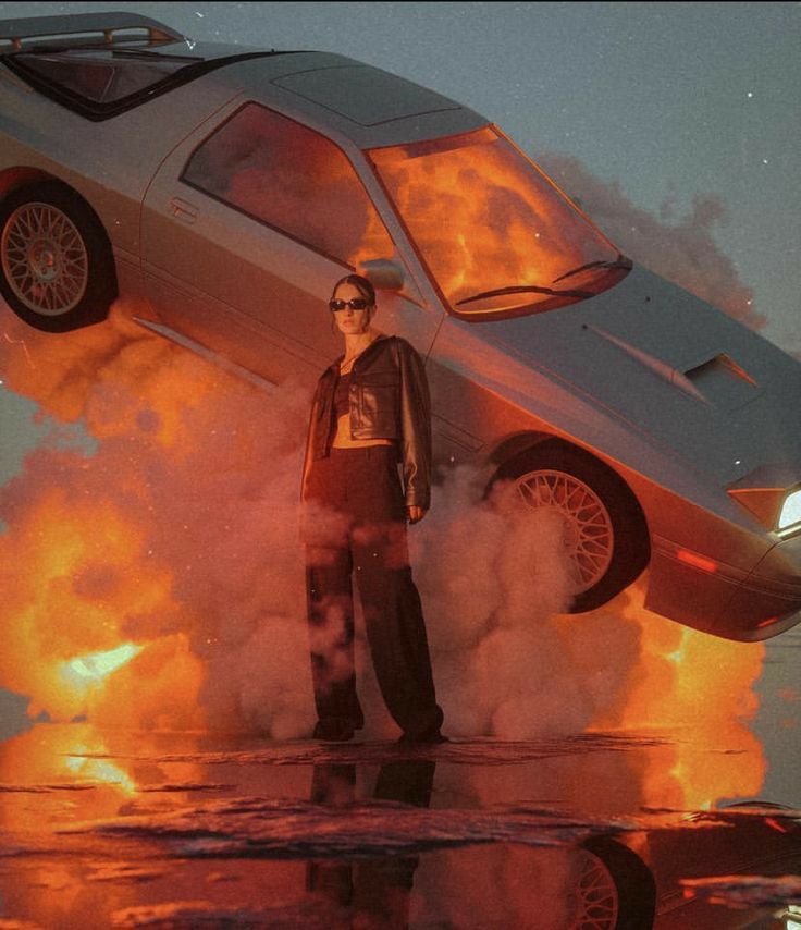 a man standing in front of a car on fire