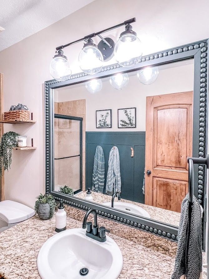 a bathroom with a sink, mirror and lights on the wall above it's counter