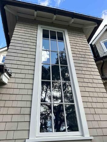 an image of a window on the side of a house that is painted gray and white