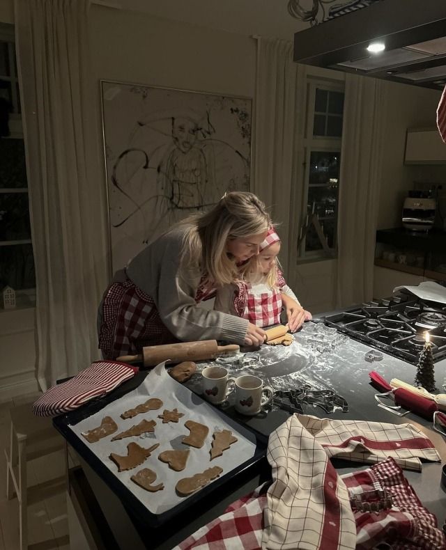 a woman and child making cookies in the kitchen