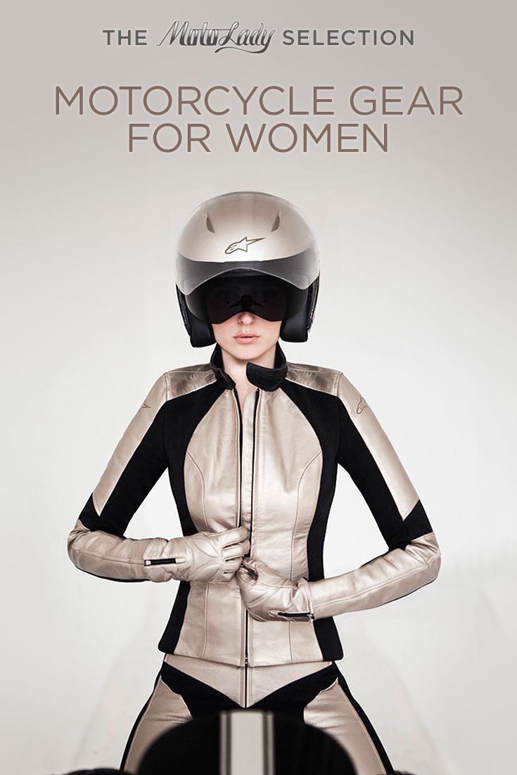 a woman with a helmet and gloves on standing in front of a white wall wearing a silver suit