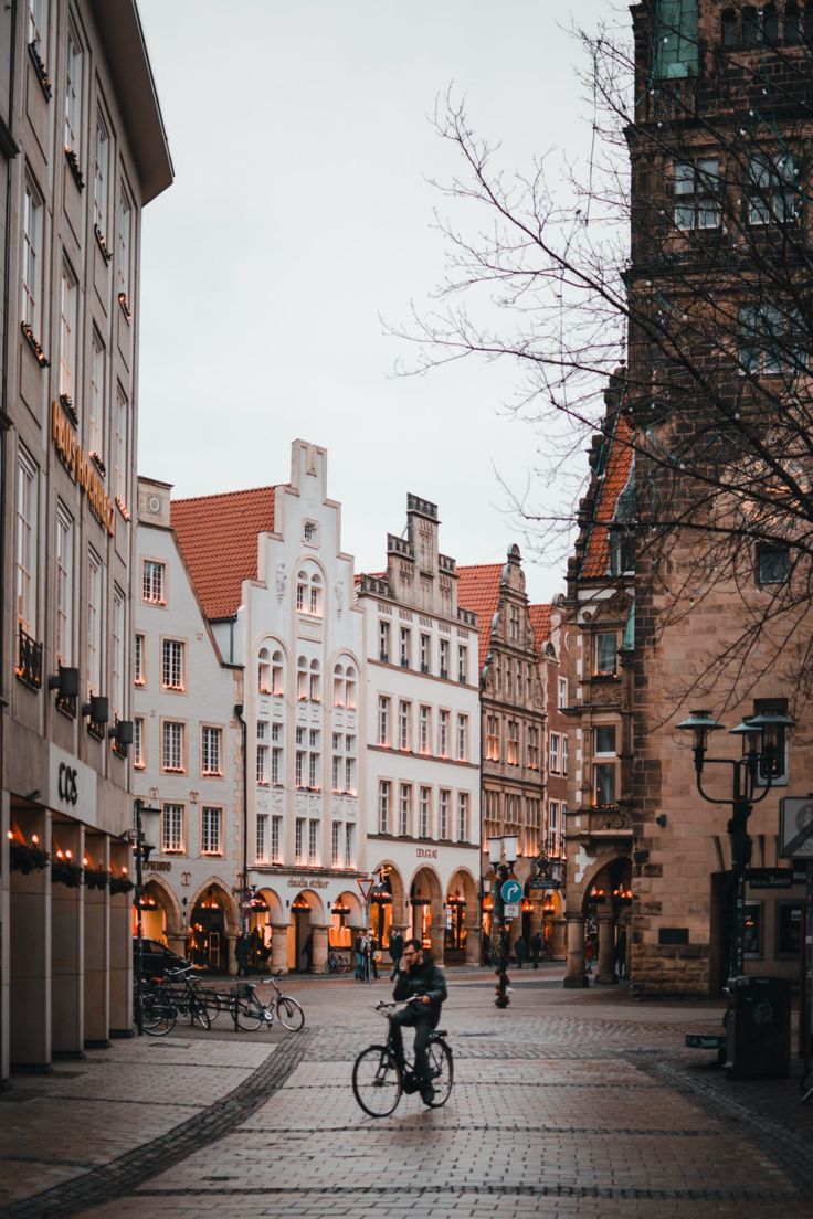 a person riding a bike on a cobblestone street in an old european city