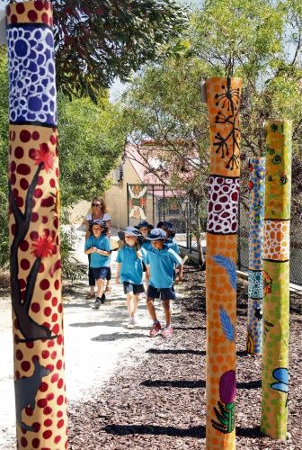 children are walking through the park with painted poles