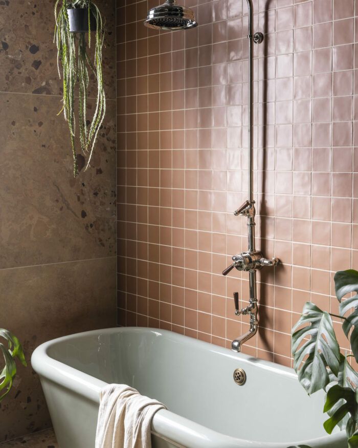 a bathroom with a bathtub, shower head and plants in the corner next to it