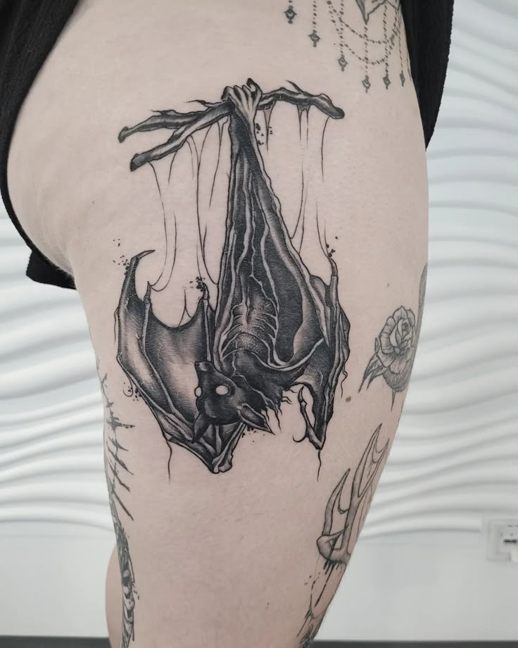 a bat tattoo on the back of a woman's thigh