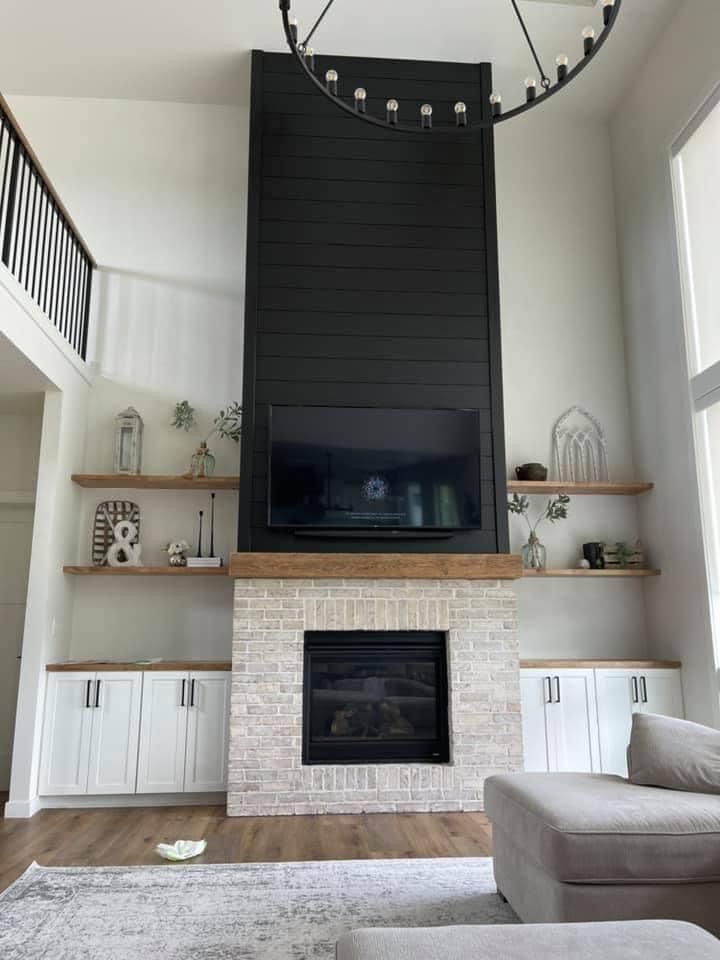 a living room with white furniture and a large tv mounted on the wall above a fireplace