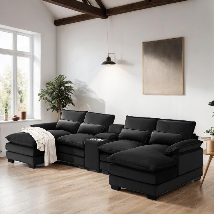 a living room with a large black couch and wooden floors in front of a window