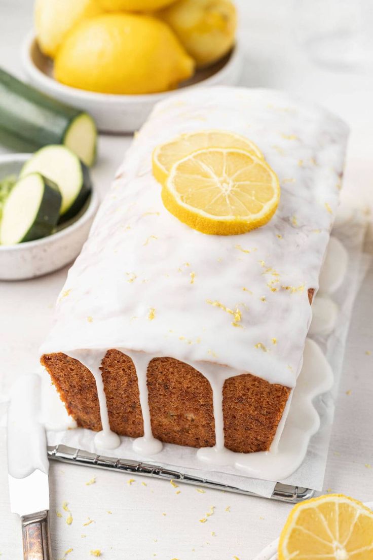 a loaf of lemon zucchini bread sitting on top of a counter next to sliced cucumbers