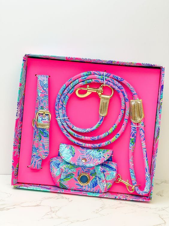 a pink box with various items in it on a white counter top and some gold hardware