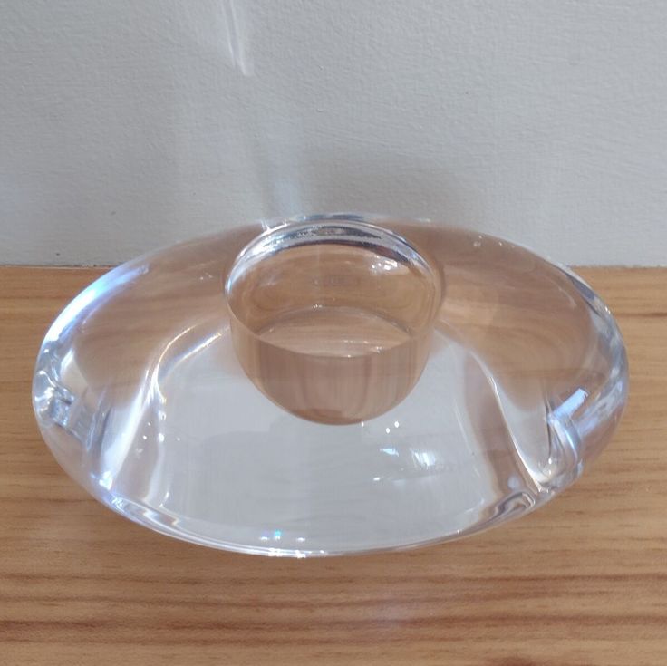 a clear glass plate with a wooden handle on a wood table top next to a white wall