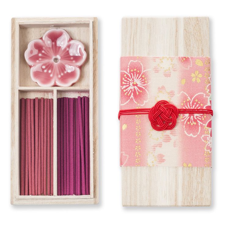 an open box with candles and a pink flower in it, next to a wooden box filled with matchesticks