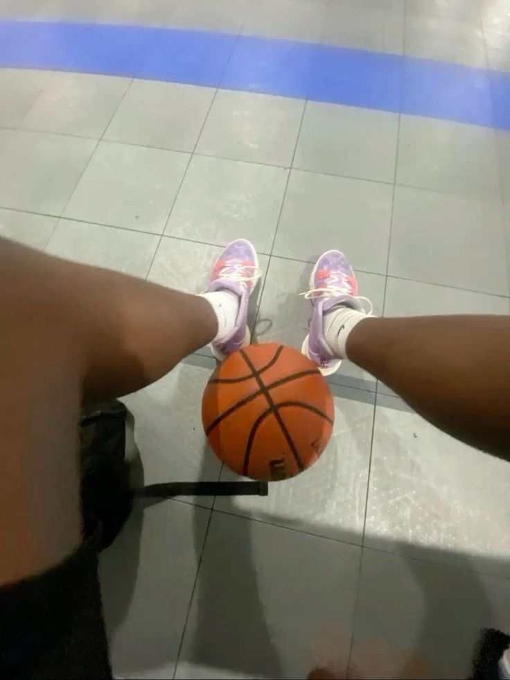 the legs of two people with shoes on, one holding a basketball