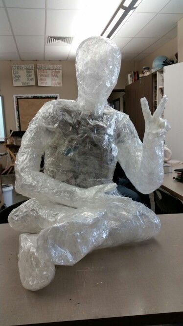 a plastic bag sitting on top of a desk next to a statue of a man