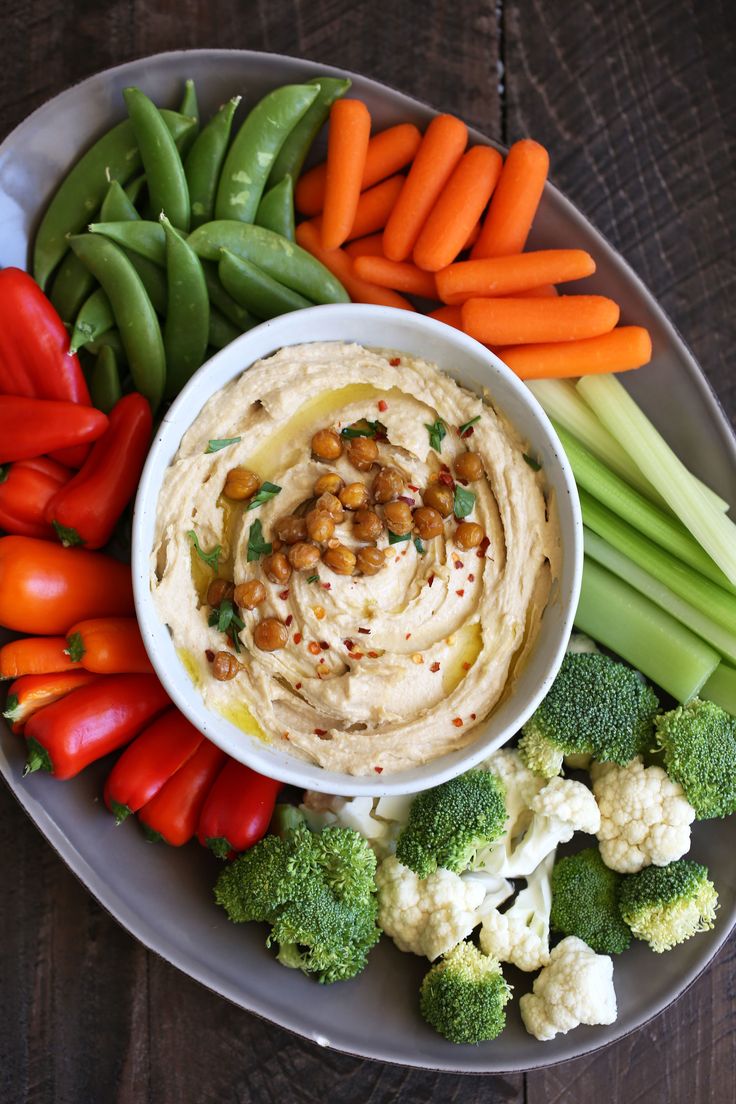 a white plate topped with vegetables and hummus