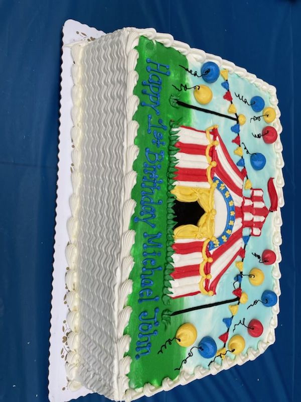 a large birthday cake with an american flag design on the top and sides, sitting on a blue table cloth