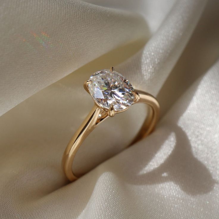 a close up view of a diamond ring on a white cloth with the light shining through it