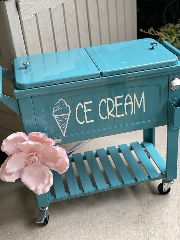 an ice cream cart with a pink flower on the front and back wheels, painted in teal