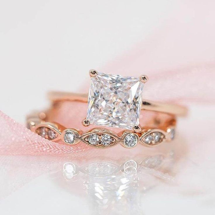 an engagement ring with a princess cut diamond in the center and side stones on each band