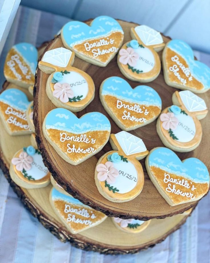 decorated cookies are arranged in the shape of hearts on top of a wooden platter