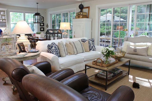 a living room filled with lots of furniture next to two large windows and white walls