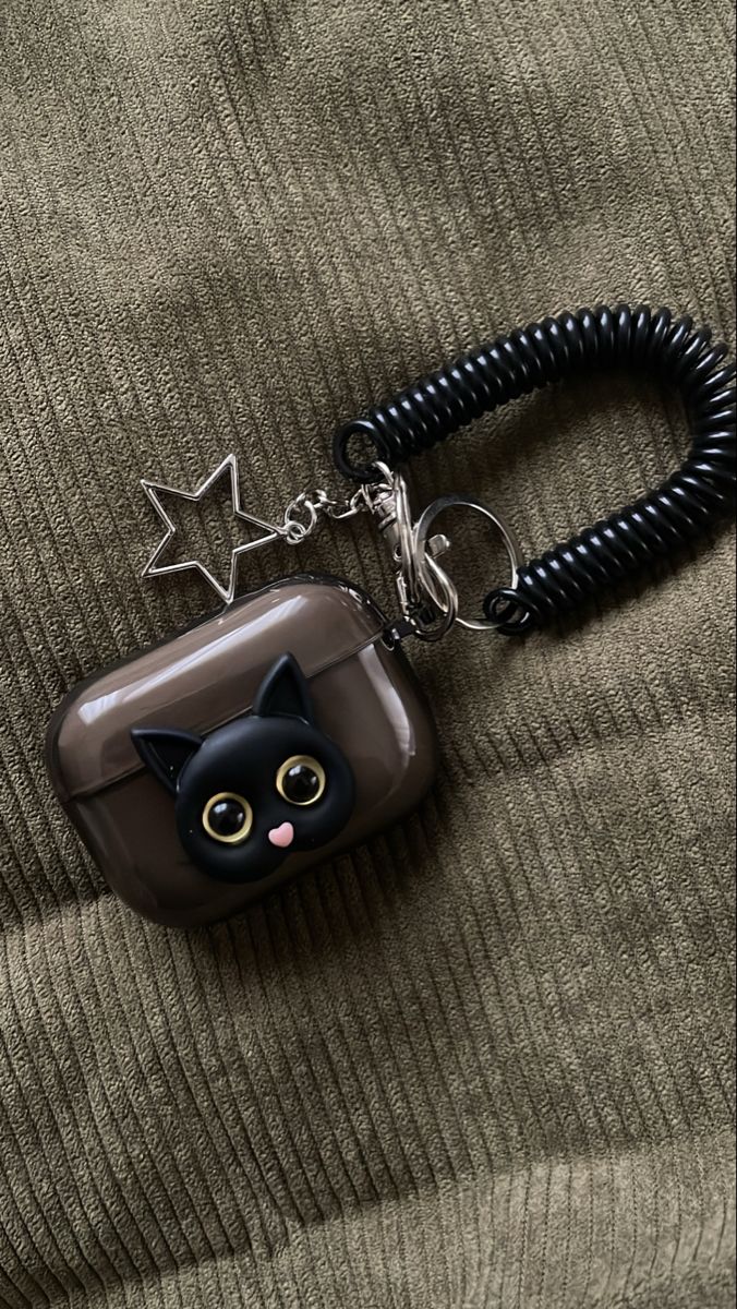 a black cat keychain on top of a green sweater with stars hanging from it's side