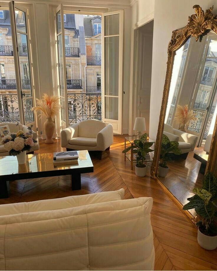 a living room filled with white furniture and lots of windows next to a wooden floor