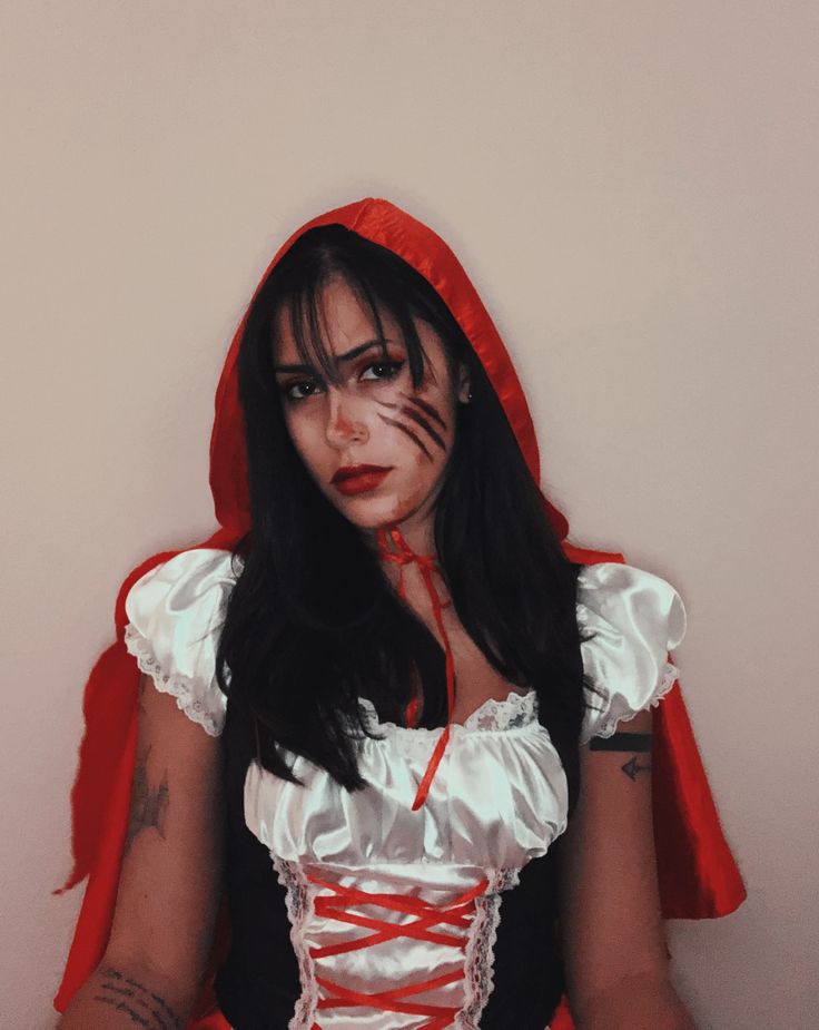 a woman in a red and white dress with her face painted like a vampire,