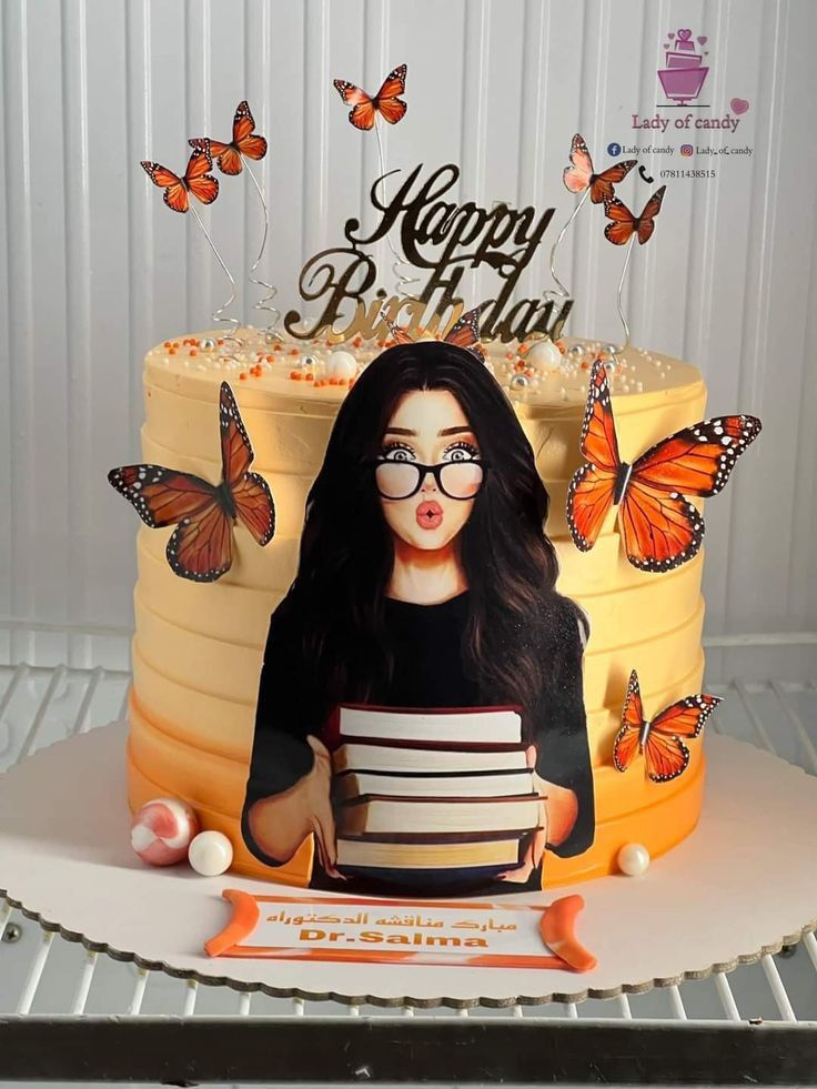 a birthday cake with a photo of a woman holding a stack of books and butterflies