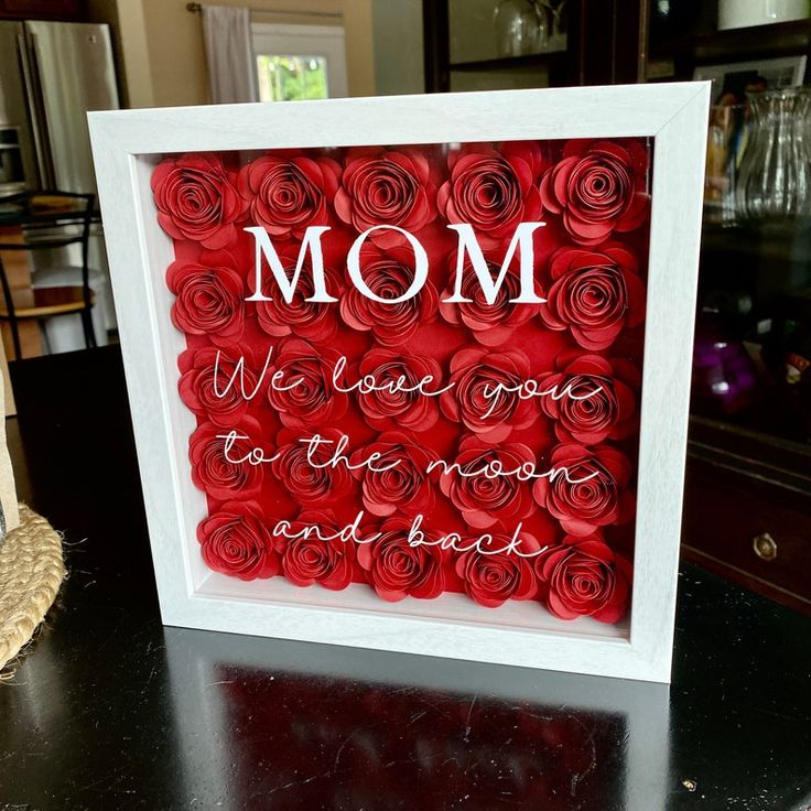 there is a picture frame with roses in the shape of flowers that say mom, we love you to the moon and back