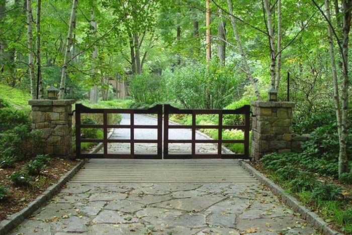 a stone walkway leading to a gate in the woods