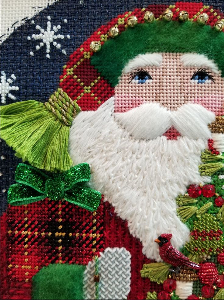 a close up of a santa clause on a piece of fabric with christmas decorations around it