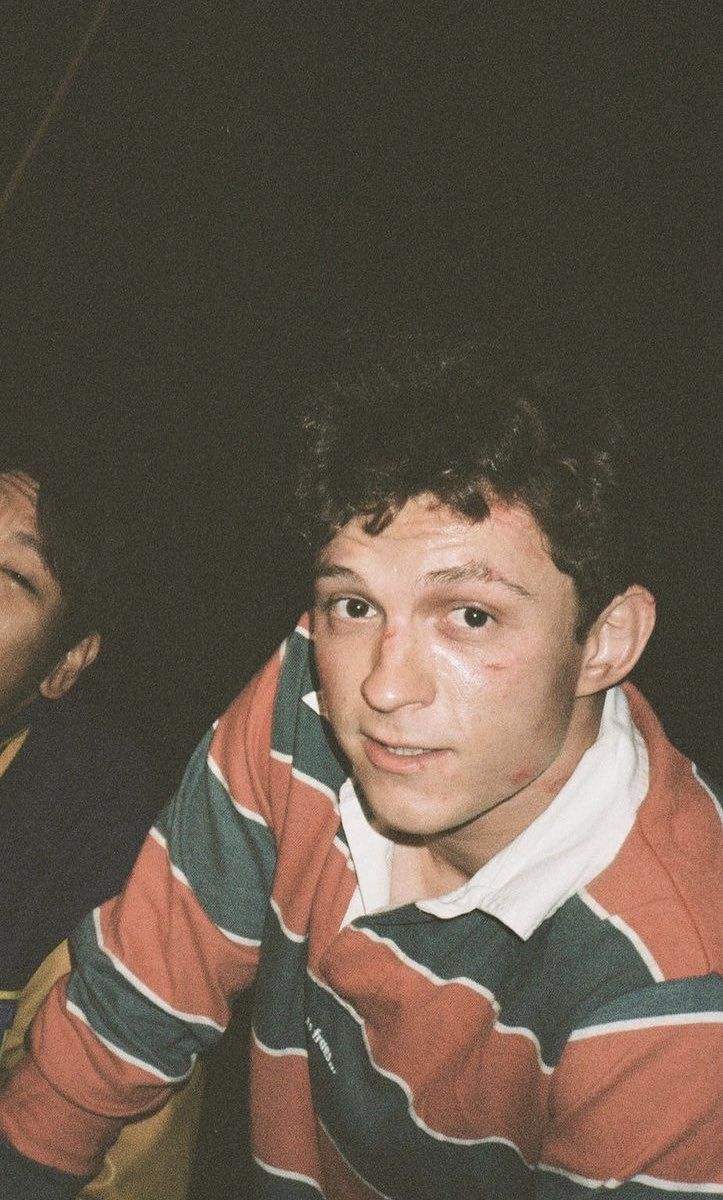 two young men sitting next to each other in front of a black background and one is looking at the camera