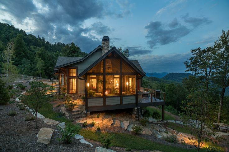 a small cabin sits on top of a hill at night with lights shining in the windows